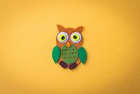 Bright felt owl craft on a vivid yellow backdrop, ideal for design projects.