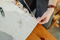 Close-up of a person weaving fabric on a wooden loom, showcasing craftsmanship and detail.