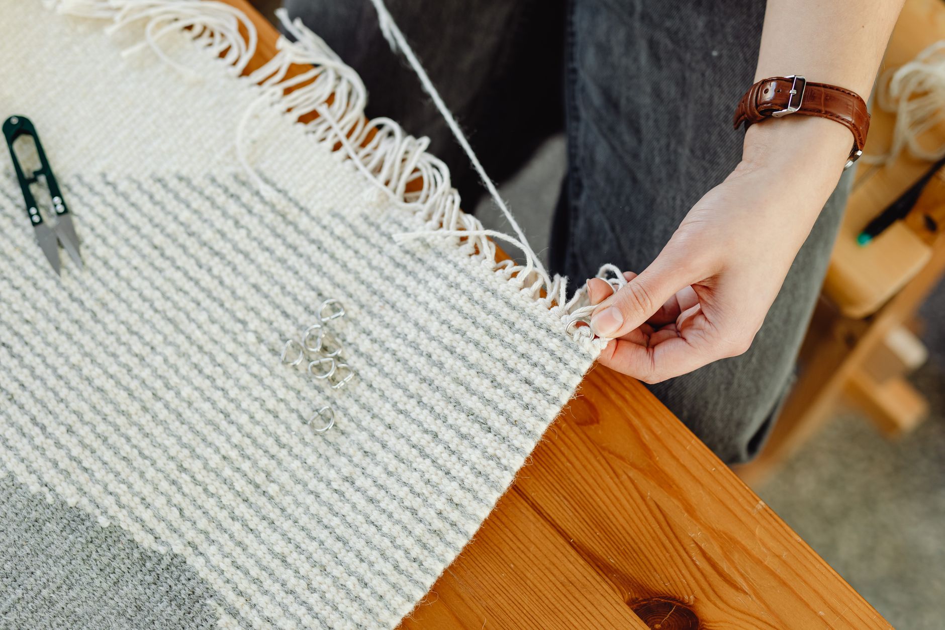 Close-up of a person weaving fabric on a wooden loom, showcasing craftsmanship and detail.