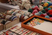 aap-craft-fair-booth-display-ideas-that-attract-crowds-1791381618 Vibrant display of handmade bracelets and crocheted keychains at a market stall.