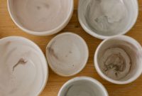 aap-how-to-make-marbled-clay-ring-dishes-1793203235 Top view of a collection of marble-textured ceramic bowls on a wooden surface.