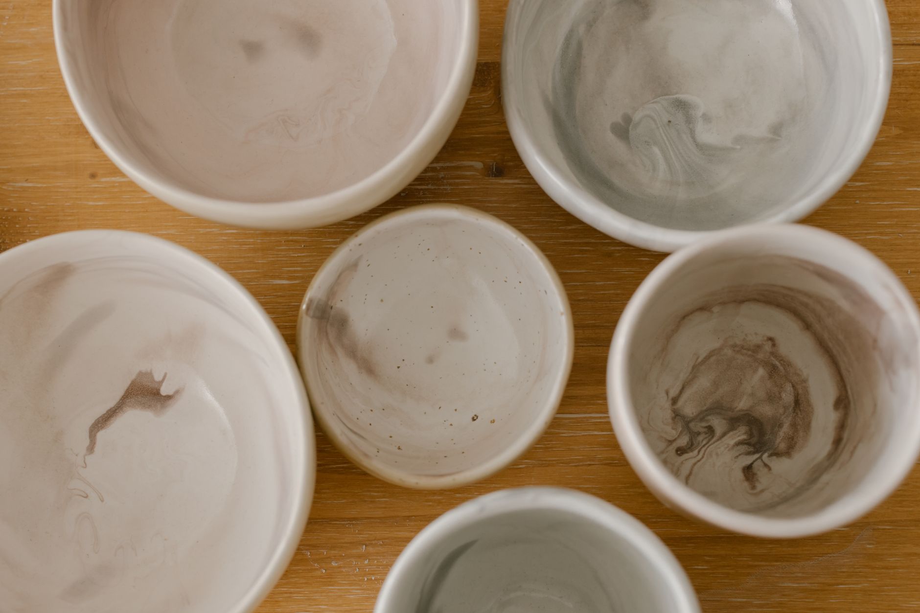 Top view of a collection of marble-textured ceramic bowls on a wooden surface.