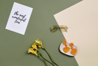 A chic summer flat lay featuring sunglasses, earrings, and flowers on colored paper.