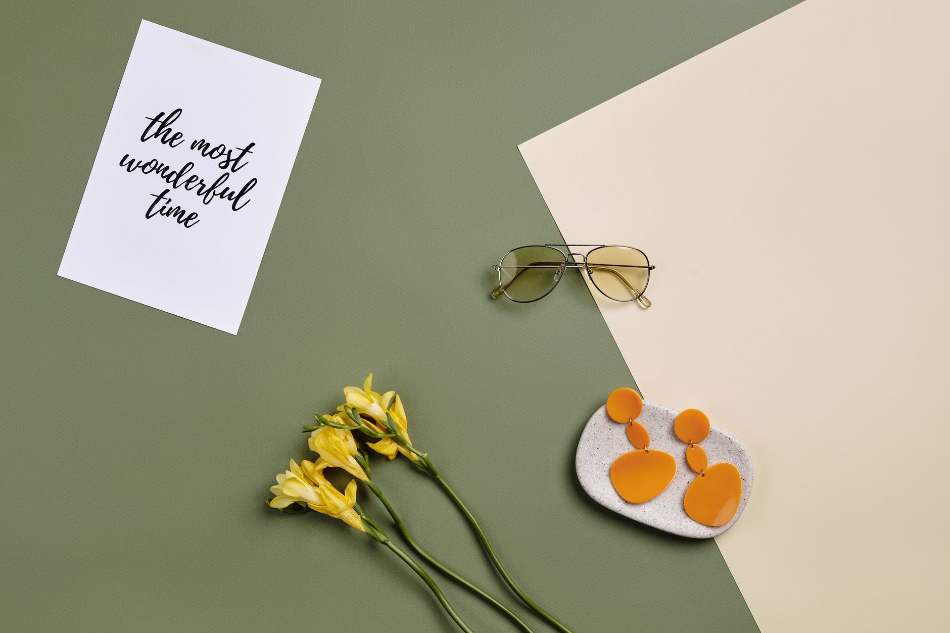A chic summer flat lay featuring sunglasses, earrings, and flowers on colored paper.